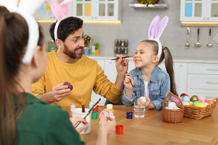 Happy family having fun while painting Easter eggs at table in kitchenの写真素材