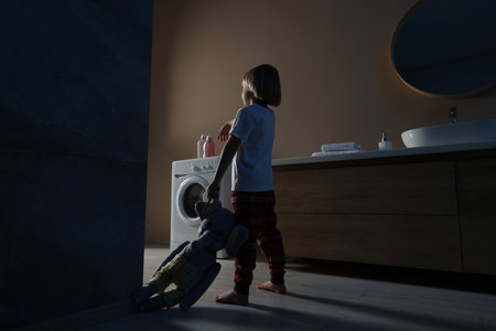 Boy in pajamas with toy elephant sleepwalking indoors at nightの写真素材