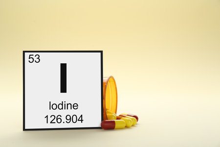 Card with iodine element, jar and pills on beige background. Space for text