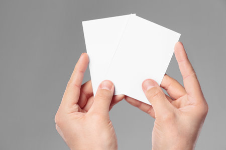 Man holding paper cards on gray background, closeup. Mockup for designの写真素材