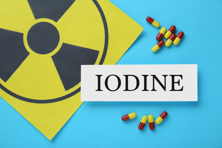 Paper note with word Iodine, radiation sign and pills on light blue background, flat layの写真素材