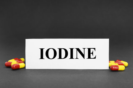 Card with word Iodine and pile of pills on black backgroundの写真素材