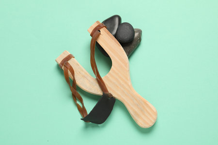 Wooden slingshot with stones on light green background, top viewの写真素材