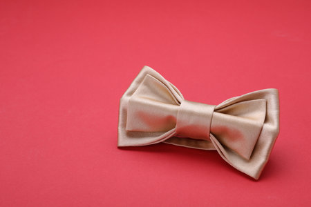Stylish beige bow tie on red background, space for textの写真素材