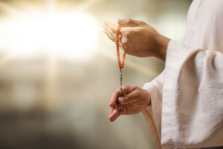 Muslim man with misbaha praying on blurred background, closeup. Space for textの写真素材