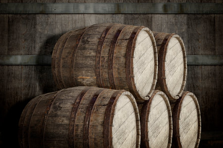 Many wooden barrels near dark textured wallの写真素材