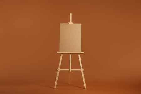 Wooden easel with blank board on brown backgroundの写真素材