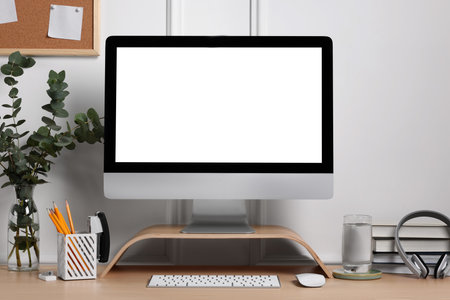 Cozy workspace with computer, headphones and stationery on wooden desk
