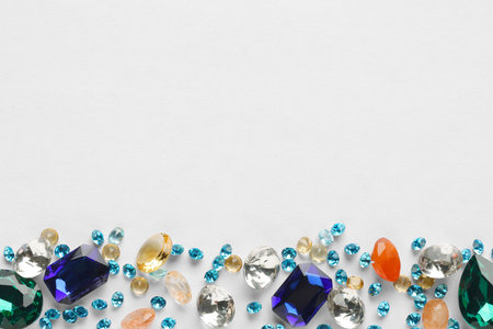 Different beautiful gemstones for jewelry on white background, top view. Space for textの写真素材