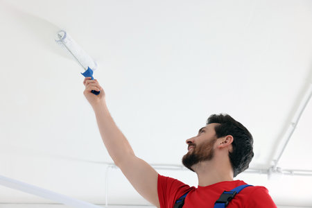 Handyman painting ceiling with roller in room, low angle viewの写真素材
