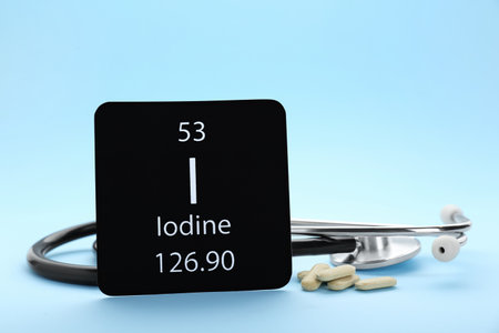 Card with Iodine element, stethoscope and pills on light blue backgroundの写真素材