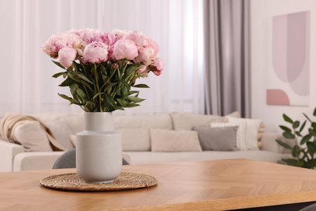 Vase with pink peonies on wooden table in dining room. Space for textの写真素材