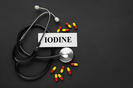 Card with the word Iodine, stethoscope and pills on black background, flat lay. Space for textの写真素材
