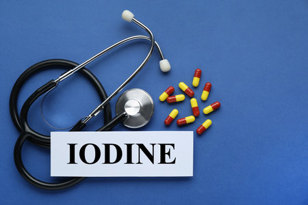 Card with word Iodine, stethoscope and pills on blue background, flat layの写真素材