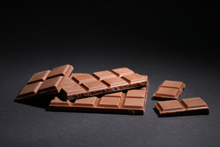 Pieces of delicious milk chocolate bars on black backgroundの写真素材
