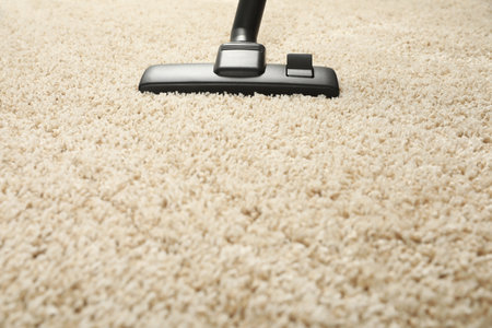 Removing dirt from beige carpet with modern vacuum cleaner. Space for textの写真素材