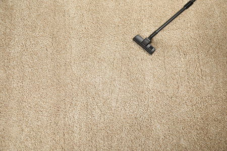 Removing dirt from beige carpet with modern vacuum cleaner, top view. Space for textの写真素材