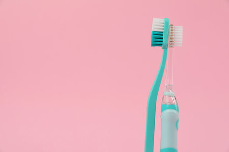 Electric and plastic toothbrushes on pink background, space for textの写真素材