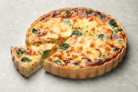 Delicious homemade quiche with salmon and broccoli on light gray tableの写真素材