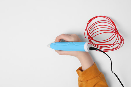 Boy drawing with stylish 3D pen on white background, top view. Space for text