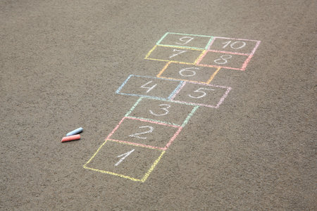 Hopscotch drawn with colorful chalk on asphalt outdoors