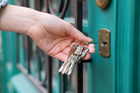 Woman opening door with key outdoors, closeupの写真素材