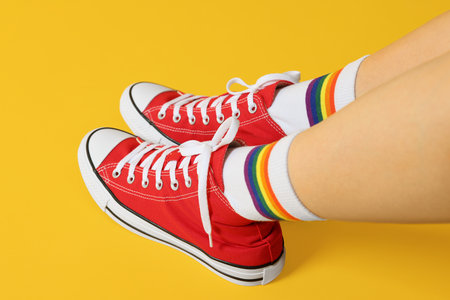 Woman in stylish gumshoes on yellow background, closeupの写真素材