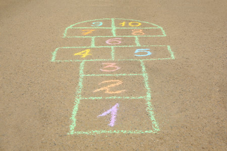 Hopscotch drawn with colorful chalk on asphalt outdoors