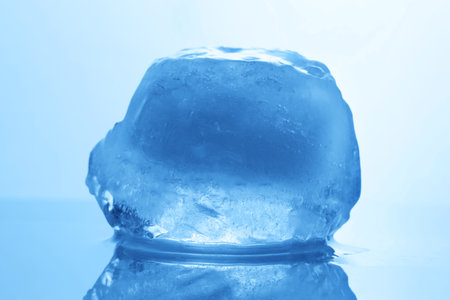Crystal clear ice cube on light blue background, closeup. Color tone effectの写真素材