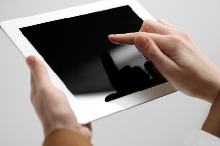 Closeup view of woman using modern tablet on light gray backgroundの写真素材