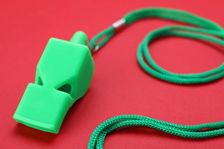 One green whistle with cord on red background, closeupの写真素材