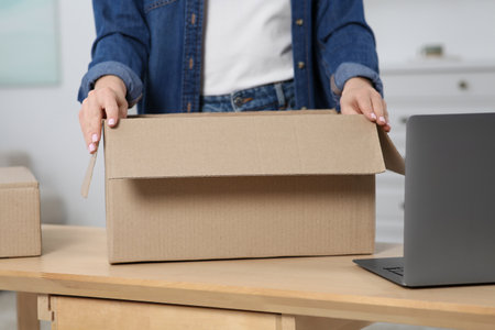 Woman unpacking parcel at home, closeup. Online store