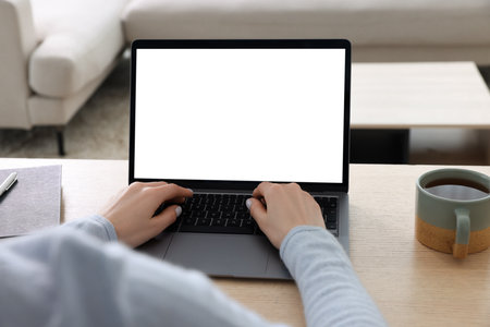 Woman working with laptop at wooden desk indoors, closeupの写真素材