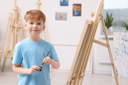 Little boy painting in studio. Using easel to hold canvasの写真素材