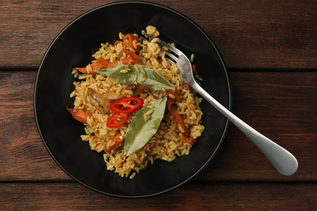 Delicious pilaf, bay leaves and fork on wooden table, top viewの写真素材