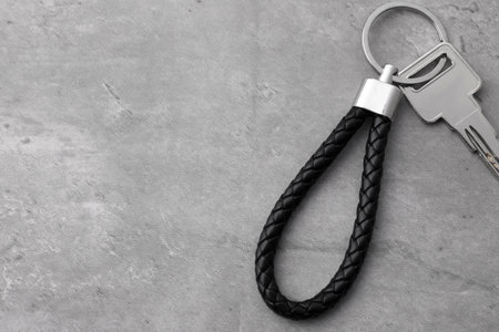 Key with black leather keychain on gray background, top view. Space for textの写真素材