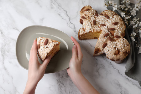 Woman with piece of delicious Italian Easter dove cake (traditional Colomba di Pasqua) at white...