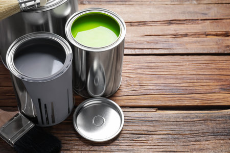 Cans of paints and brushes on wooden table, space for textの写真素材