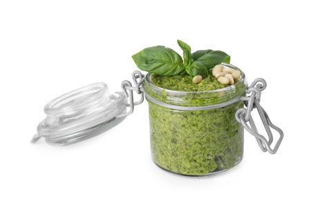 Delicious pesto sauce, pine nuts and basil leaves in jar isolated on whiteの写真素材