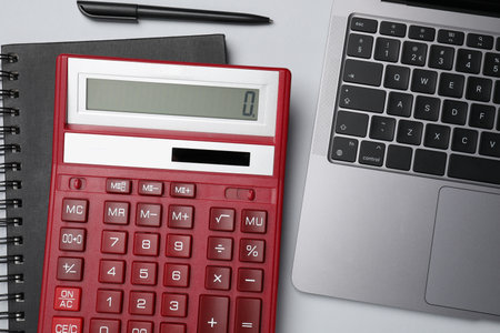 Calculator, laptop, notebook and pen on white background, flat lay