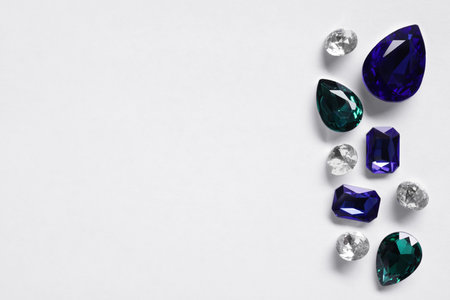 Different beautiful gemstones for jewelry on white background, top view. Space for textの写真素材
