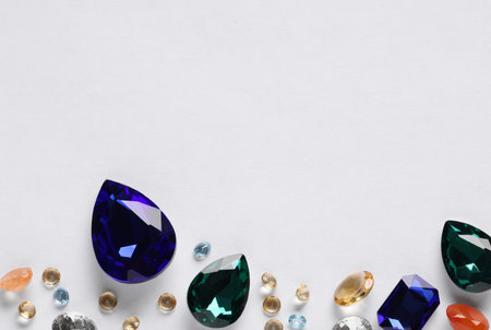 Different beautiful gemstones for jewelry on white background, top view. Space for textの写真素材