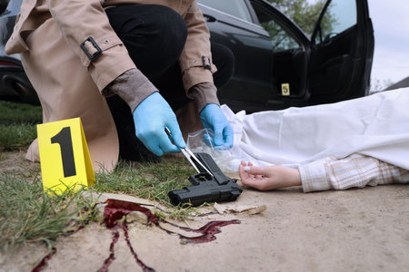 Investigator in protective gloves working at crime scene with dead body outdoors, closeupの写真素材