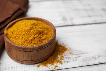 Bowl with curry powder on white wooden table, closeup. Space for textの写真素材