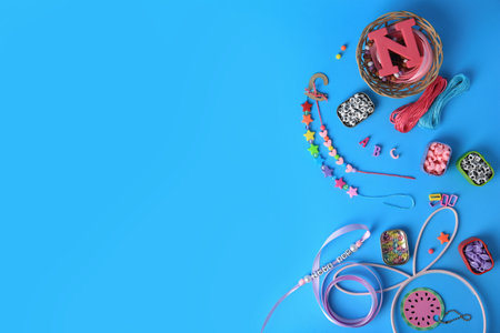 Kid`s handmade jewelry kit. Colorful beads, ribbon and bracelets on light blue background, flat lay....