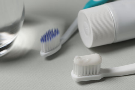 Plastic toothbrush with paste on gray background, closeup