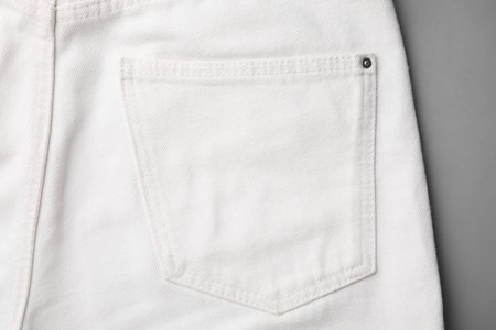 White jeans with pocket on gray background, top view