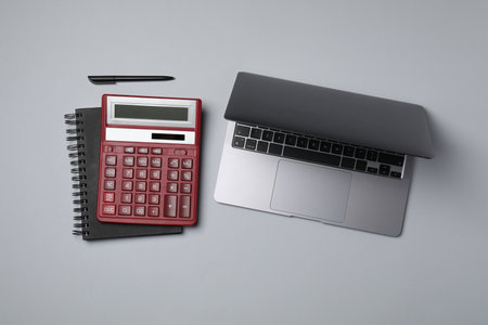Calculator, laptop, notebook and pen on light gray background, flat layの写真素材