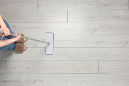 Woman mopping wooden floor, top view. Space for textの写真素材
