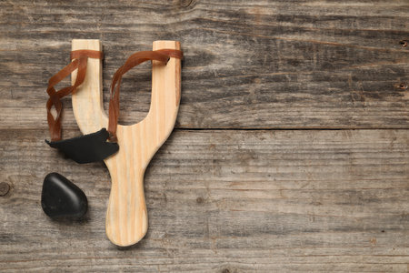 Slingshot with pebble on wooden background, top view. Space for textの写真素材